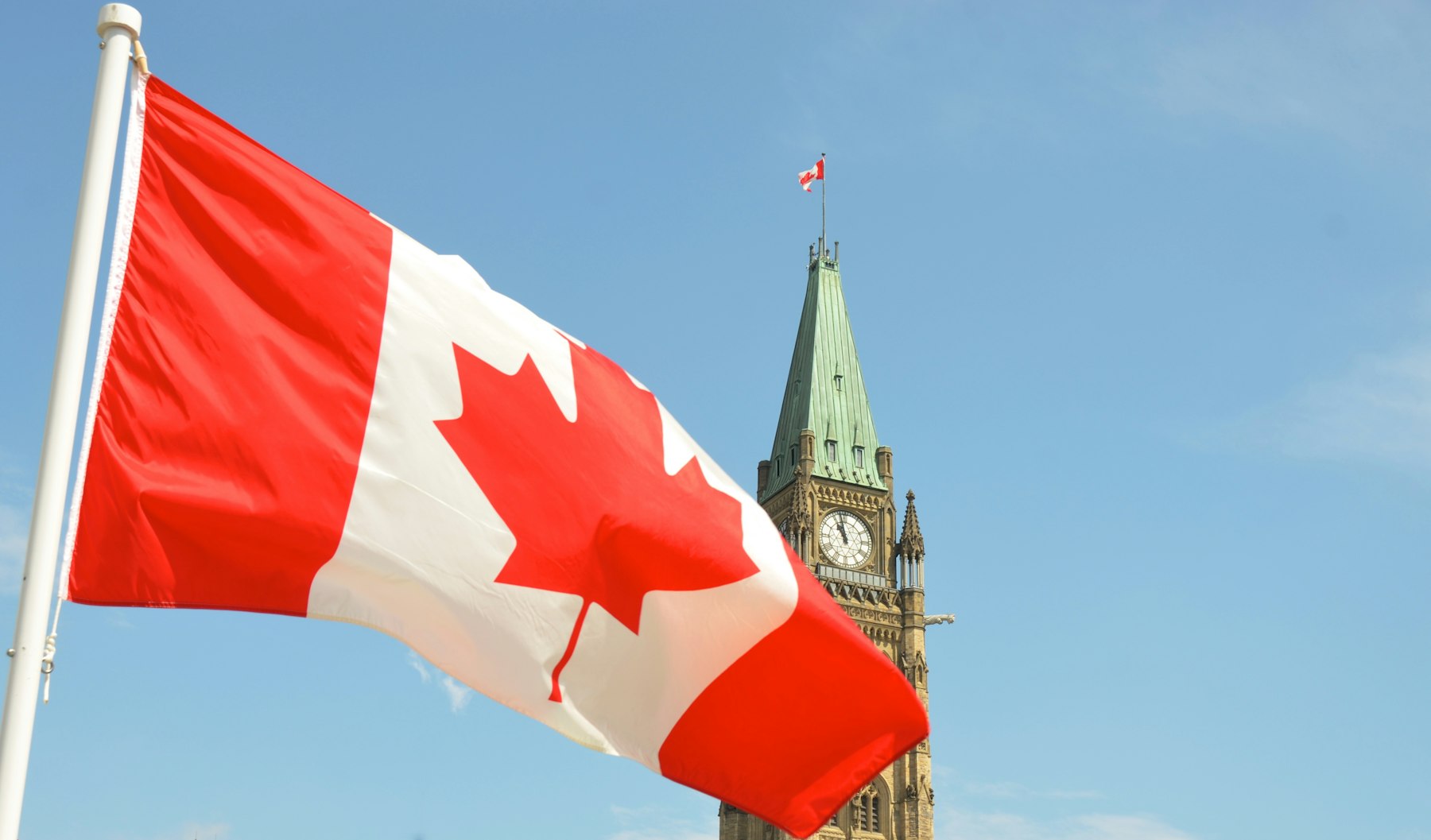 The Canadian flag flying in front of the Peace Tower on Parliament Hill in Ottawa